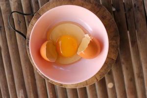 skal med ägg och öppen ägg i en rosa skål placerad på de slaktare på bambu battens.top se närbild. foto