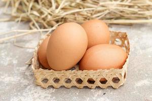 färsk brun ägg i korg- skål isolerat. lugg av rå kyckling ägg på ris sugrör bakgrund. foto
