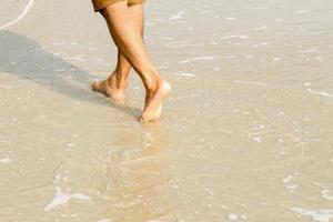 mänsklig fötter gående på de strand, turist koppla av på sommar Semester. foto