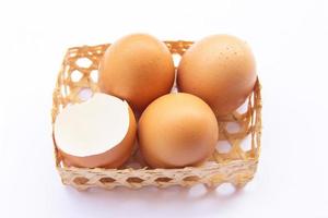 brun kyckling ägg är placerad i bambu brickor. med ett äggskal på en vit bakgrund foto
