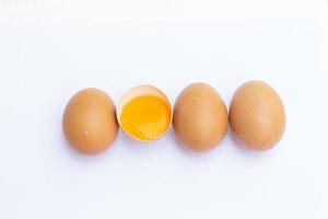 fyra brun ägg anordnad i en rad på en vit bakgrund och där var ett ägg bruten i halv, och fick syn på de äggula i Det. foto
