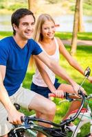 ridning cykel är roligt skön ung leende par ridning deras cyklar i parkera tillsammans foto