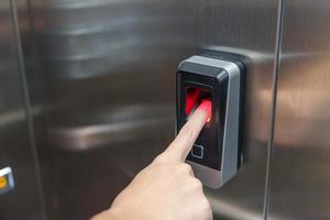 kvinna använder sig av finger till fingeravtryck scanner i hiss. säkerhet systemet i kontor och lägenhet begrepp foto