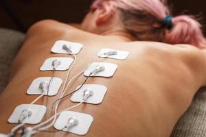myostimulering elektroder på en kvinnas tillbaka för massage och rehabilitering. foto