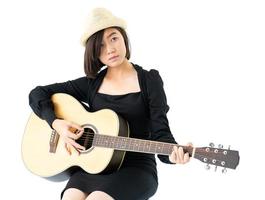 kvinna sitter och spelar gitarr gitarr folksång i hennes hand foto