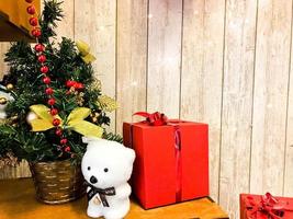 liten söt polär Björn under de ny år elegant skön jul träd. ny år Semester dekoration och gåva röd låda foto