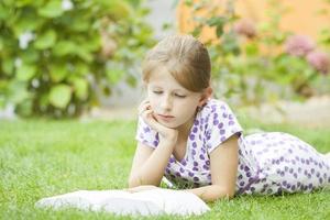 flicka som läser en bok i parken