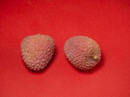 litchi på de tabell. kinesisk plommon på en röd bakgrund. mogen frukt från Asien. foto