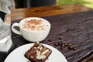 varm cappuccino i vit kopp med trä- bakgrund, kaffe är en populär dryck Allt över de värld. foto