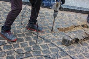 en manlig arbetstagare reparationer de trottoar med en jackhammer. de arbete av de kommunal service foto