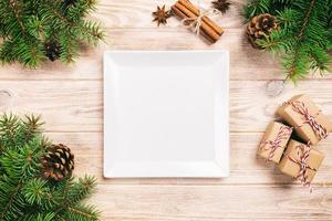 vit fyrkant tallrik på en trä- tabell. med jul dekoration, fyrkant tömma maträtt. ny år begrepp foto