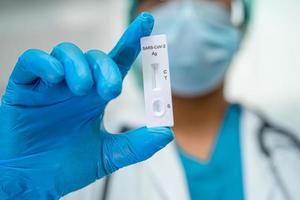 Asiatisk läkare i ppe-dräkt som håller testkit för salivantigen för att kontrollera covid-19 coronavirus på sjukhus. foto