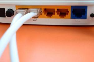 de internet kabel- pluggar är ansluten till de internet router, som lögner på en ljus orange bakgrund. objekt nödvändig för internet förbindelse foto