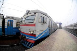 de järnväg Spår i en dimmig morgon. de ukrainska förorts tåg är på de passagerare station. fisköga Foto med ökade förvrängning