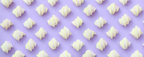 färgrik marshmallow lagd ut på violett papper bakgrund. pastell kreativ texturerad mönster. minimal foto