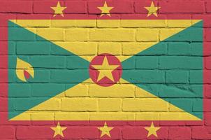 grenada flagga avbildad i måla färger på gammal tegel vägg. texturerad baner på stor tegel vägg murverk bakgrund foto