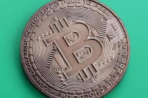 choklad produkt i de form av fysisk bitcoin lögner på en grön plast bakgrund. modell av de crypto valuta i de ätlig form foto
