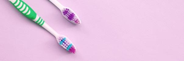 två tandborstar lögn på en pastell rosa bakgrund foto