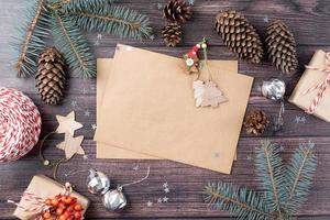hantverk kuvert med jul dekorationer och tall koner topp se på trä- bakgrund foto