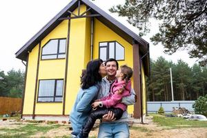 Lycklig familj i de gård av ett oavslutat hus - inköp av en stuga, inteckning, lån, flytt, konstruktion foto