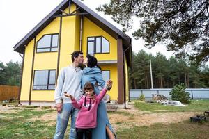 Lycklig familj i de gård av ett oavslutat hus - inköp av en stuga, inteckning, lån, flytt, konstruktion foto