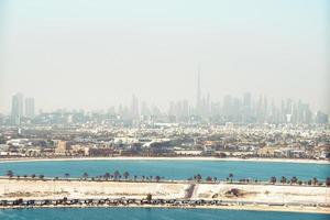 dubai stadens centrum horisont med strand från sharjah distrikt, förenad arab emirates eller uae. finansiell distrikt i resa semester begrepp. skyskrapor byggnader med dimmig förorenad himmel. foto