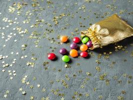 färgrik godis i de guld säck på grå bakgrund med stjärnor foto