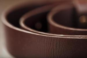 modern herr- brun bälte tillverkad av äkta läder med en ljus metall spänne på en mörk bakgrund. äkta läder, handgjort foto
