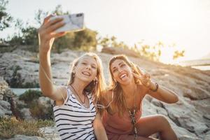 två kvinna vänner har roligt medan tar en selfie på sommar semester foto