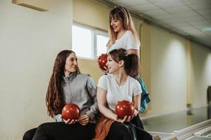 en tre kvinna vänner har roligt i en bowling gränd foto
