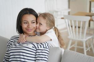 liten förskola dotter kel främja mor, som visar kärlek, njuter kramar tillsammans på Hem foto