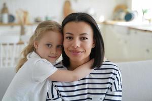 liten antogs dotter kramas främja mor, Sammanträde på soffa på Hem. Lycklig moderskap, adoption foto