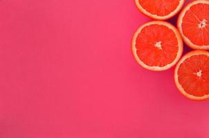 topp se av en flera grapefrukt skivor på ljus bakgrund i rosa Färg. en mättad citrus- textur bild foto