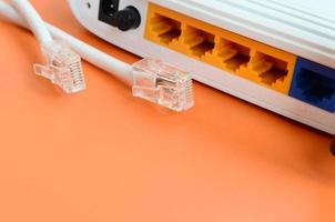 internet router och internet kabel- pluggar lögn på en ljus orange bakgrund. objekt nödvändig för internet förbindelse foto