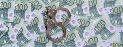 polis handklovar lögner på en uppsättning av grön monetär valörer av 100 euro. en massa av pengar former ett oändlig högen foto