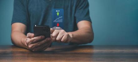 ung man näringsidkare handel uppkopplad på de smartphone appar för köpa och sälja stock finansiell marknadsföra med Diagram. foto