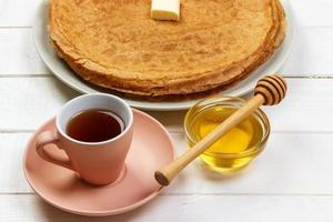 frukost te med pannkakor och honung på trä- bakgrund foto