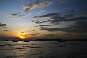 silhuett av fartyg och lång svans båt på hav eller hav med blå himmel och moln på solnedgång, soluppgång eller skymning tid på krabi, thailand. skönhet i natur med Vinka och transport begrepp foto