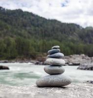 en pyramid av bar stenar staplade på topp av varje Övrig. stenar staplade i de form av en pyramid på de flodbank mot de bakgrund av bergen som balans och balans i natur, zen, buddhism. foto