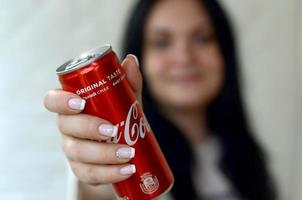 kharkov. ukraina - Maj 2, 2022 Lycklig kvinna innehav alkoholfri Coca Cola aluminium tenn kan i garage interiör foto