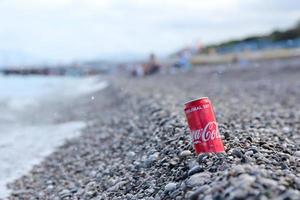 antalya, Kalkon - Maj 18, 2022 original- coca cola röd tenn kan lögner på små runda sten stenar stänga till hav Strand. Coca Cola på turkiska strand foto