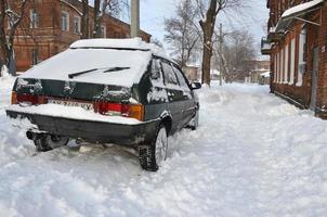 Kharkov, ukraina - januari 4, 2022 en parkerad bil under en tjock lager av snö. konsekvenser av en stark och oväntat snöfall i ukraina foto