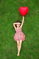 vacker flicka som ligger på gräset och håller den röda bollen