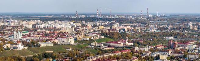 Ariel panorama- se av gammal stad och modern skyskrapor med en enorm fabrik med rökning skorstenar i de bakgrund foto