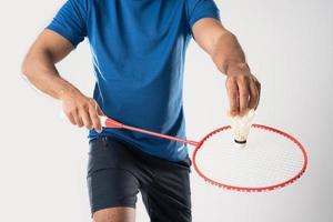 en badminton spelare i sportkläder står innehav en racket och fjäderboll. foto