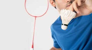 en badminton spelare i sportkläder står innehav en racket och fjäderboll. foto