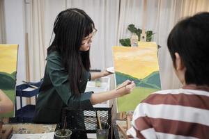 en kvinna asiatisk lärare lär och demonstrerar till de barn på akryl Färg bild målning på duk i konst klassrum, kreativt inlärning med skicklighet på de elementärt skola studio utbildning. foto