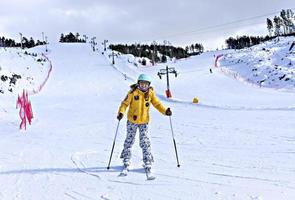 Lycklig leende ung kvinna i gul jacka och åka skidor hjälm skidåkning på en berg backe, vinter- sporter, alpina skidåkning utomhus aktivitet, friska livsstil foto