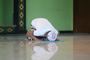 ung asiatisk muslim bön- i de moské foto