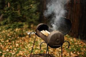 utegrill grill i de öppen luft med trän och rök i höst. foto